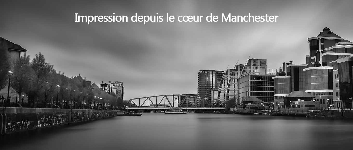 une photo en noir et blanc d'une rivière avec un pont en arrière-plan